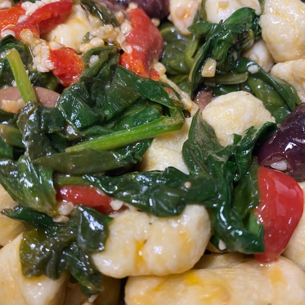 Close-up of Mona Lisas Ristorante's gnocchi with spinach, red peppers, and olives.